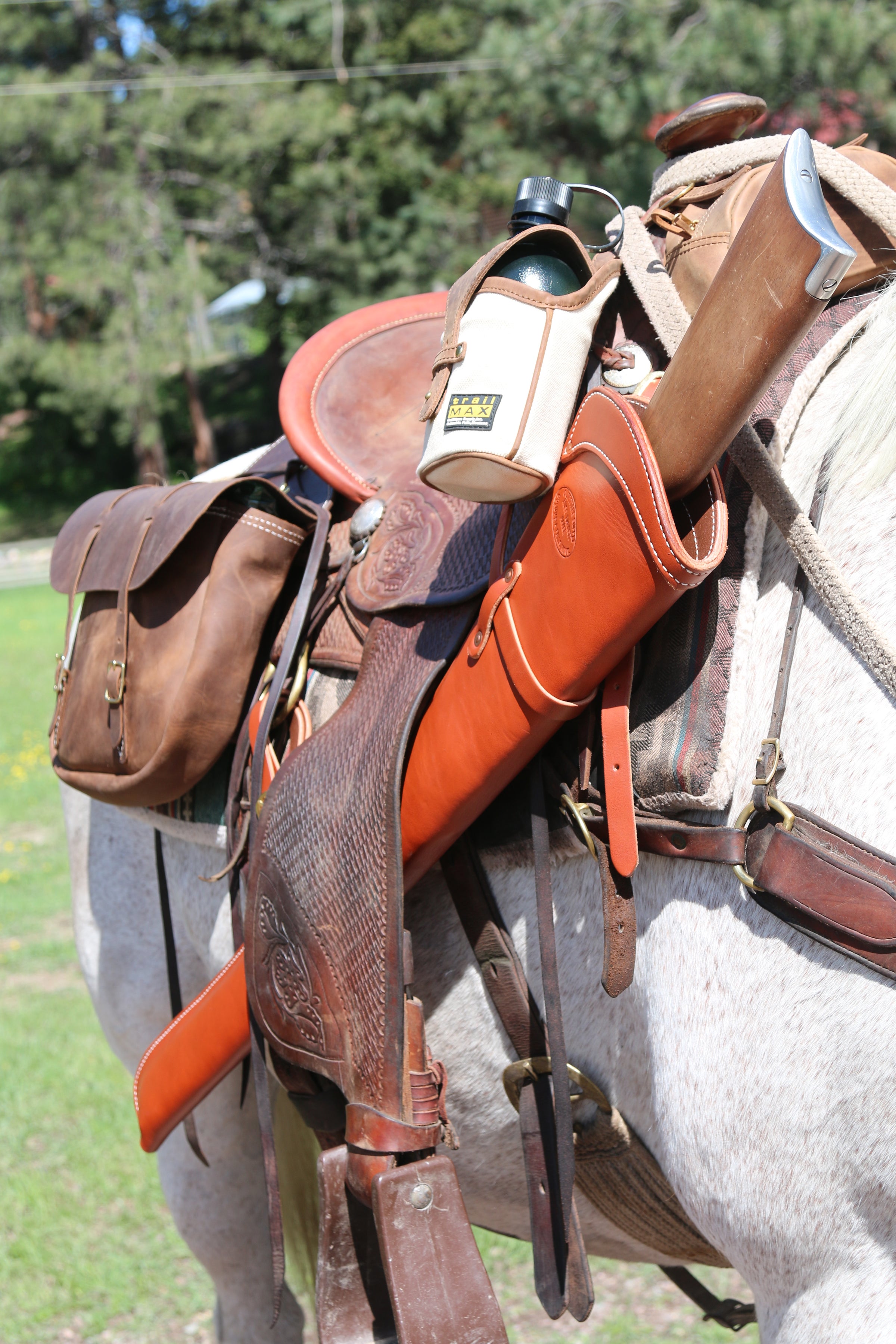 Outfitters Supply handmade leather rifle scabbard secured to a riding saddle. Also pictured is the TrailMax Canvas and leather canteen holder